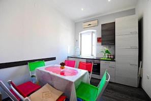 Une cuisine compacte avec une fenêtre, un coin repas comprenant une table et des chaises, et un four encastré.