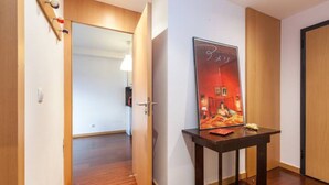 A hallway with wooden flooring, a door on the right, and a poster on the wall. - GuestReady - Broken Record with Balcony + Parking (Porto)