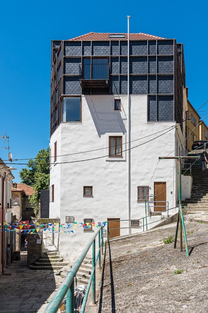 A multi-story building with a white facade and a tiled roof.