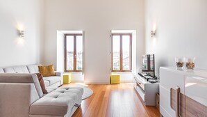 Ein modernes Wohnzimmer mit einem grauen Sofa, einem Fernseher und einem weißen Schrank.