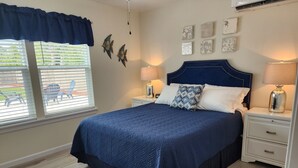 Un dormitorio con una cama grande, dos mesitas de noche, una ventana con persianas y decoración en la pared.