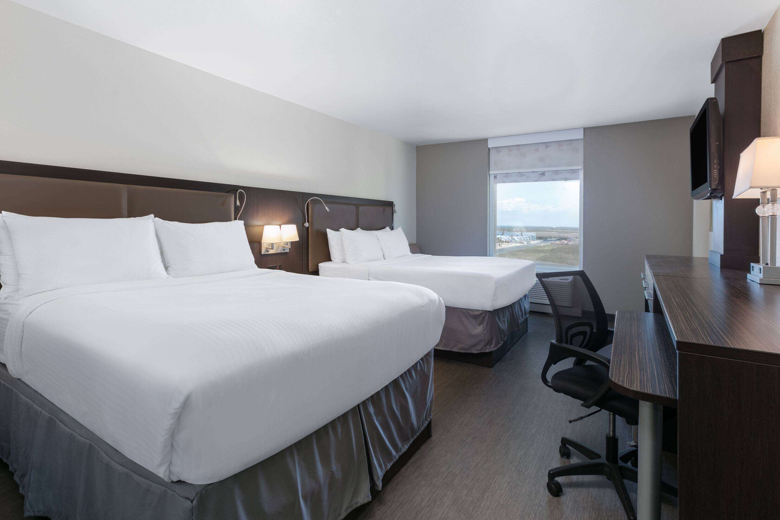 Ein Hotelzimmer mit zwei Betten, einem Schreibtisch, einem Stuhl und einem Fernseher.