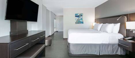 Una habitación de hotel con cama, televisión, escritorio y un cuadro en la pared.