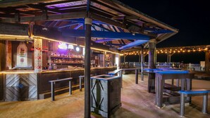 An outdoor bar area with a wooden structure, bar counter, and seating.