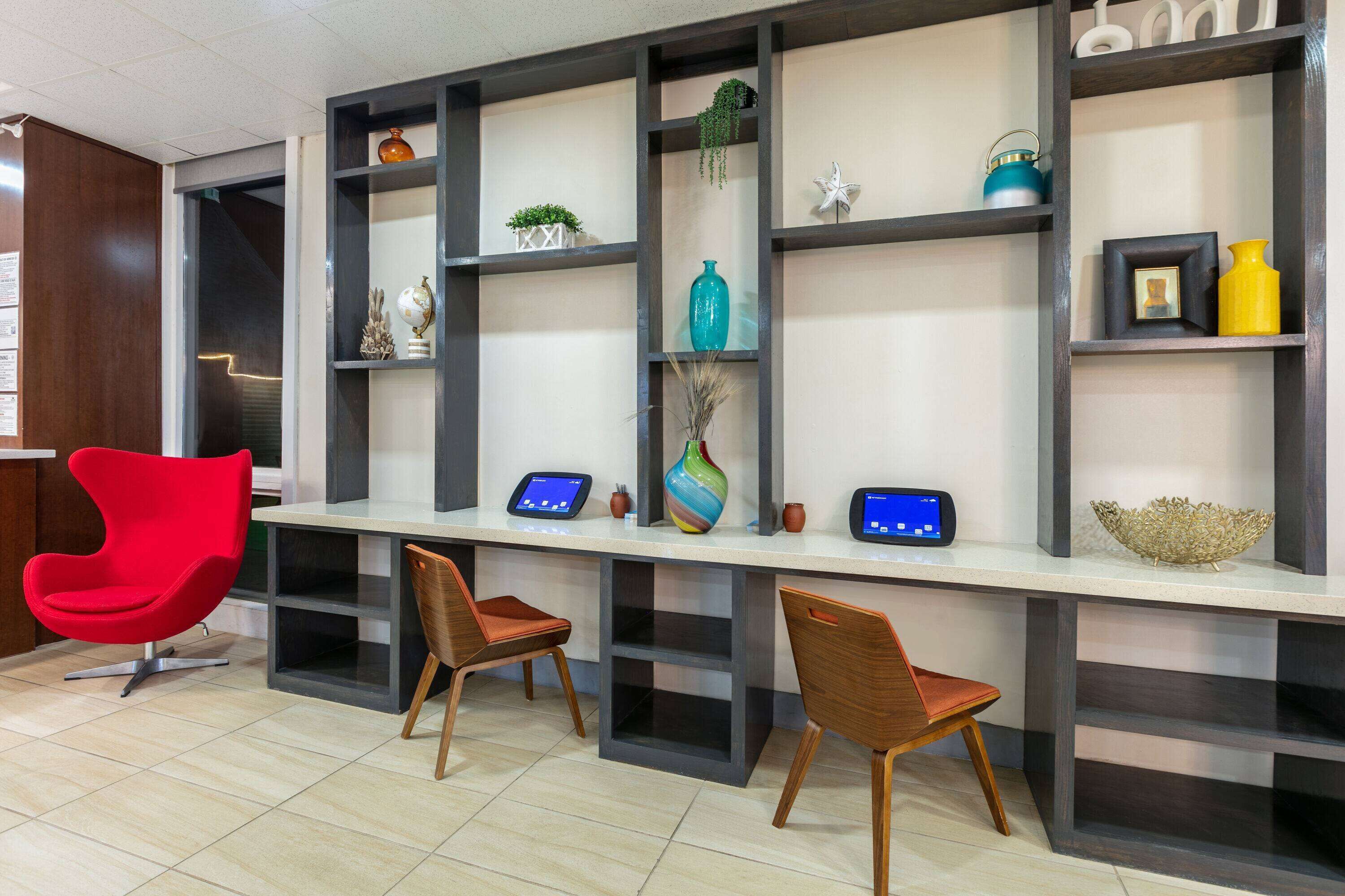 A modern office space with a long desk, two chairs, and decorative shelves.