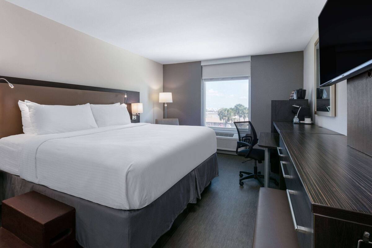 Hotelkamer met een groot bed, een bureau, een stoel, een televisie en een raam met uitzicht.