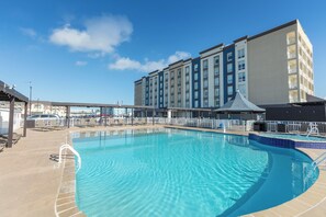 A hotel with a swimming pool, a covered area, and a parking lot.
