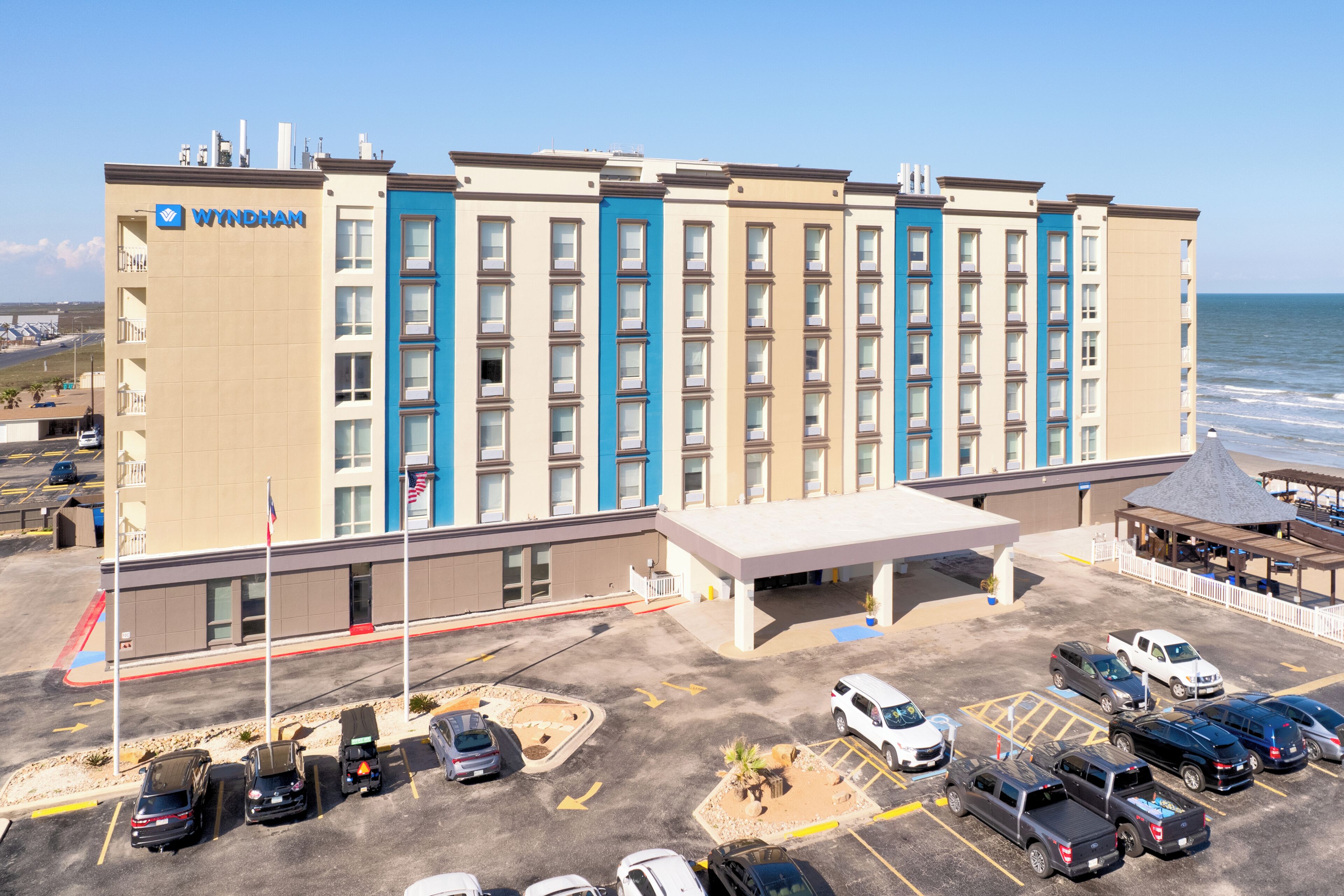 A hotel with a parking lot, a covered area, and a view of the ocean.