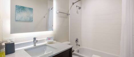 A bathroom with a large mirror, a sink, a toilet, and a bathtub.