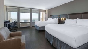 A hotel room with two beds, a desk, and a chair.