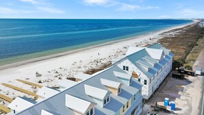 A beachfront hotel with a long building overlooking the ocean, a sandy beach, and a clear blue sky. - Pelican's Perch (Port St. Joe)