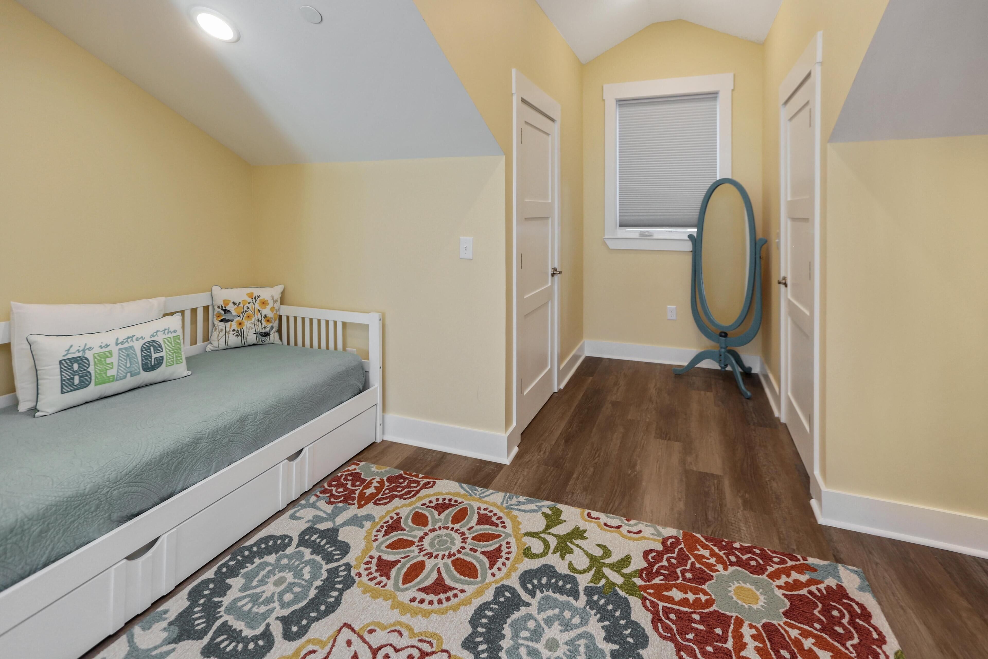 A bedroom with a bed, a window, a door, and a rug.