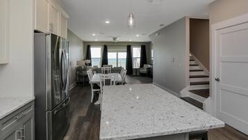 A modern kitchen with a large island, stainless steel appliances, and a dining area with a view of the ocean.