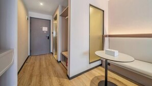 Un couloir d’hôtel moderne avec un plancher en bois, un banc, une petite table et une porte.