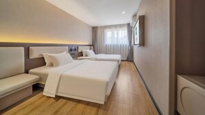 Une chambre d’hôtel avec deux lits, un canapé, une table de chevet et une fenêtre avec des rideaux.