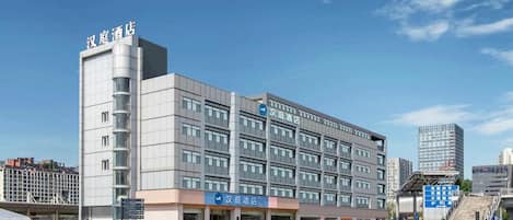Un moderno edificio de hotel con varios pisos, un letrero llamativo y un cielo despejado.