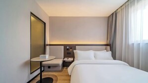 Une chambre d’hôtel moderne avec un grand lit, une petite table, une chaise et une table de chevet.