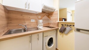 A compact kitchen with a sink, coffee maker, and a washing machine. - AS21600-P2Cabin 200m from the beach and parking (LE GRAU DU ROI)