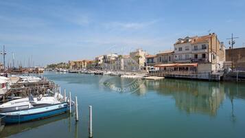 A marina with boats docked, buildings with balconies, and a clear sky.