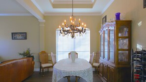 A dining area with a round table covered in a white lace tablecloth, surrounded by four chairs. A chandelier hangs from the ceiling, and a wine rack is visible to the right. - West Plano Stay – Private Retreat Near AT&T Stadium for FIFA 2026 (Plano)