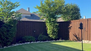 A well-maintained lawn with a wooden fence, a potted plant, and a gravel path. - West Plano Stay – Private Retreat Near AT&T Stadium for FIFA 2026 (Plano)