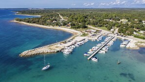 An aerial view of a coastal marina with boats docked, a pier, and surrounding residential areas. - Holiday apartment with air conditioning and barbecue (Peroj)