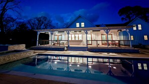 A two-story house with a covered patio and a swimming pool.