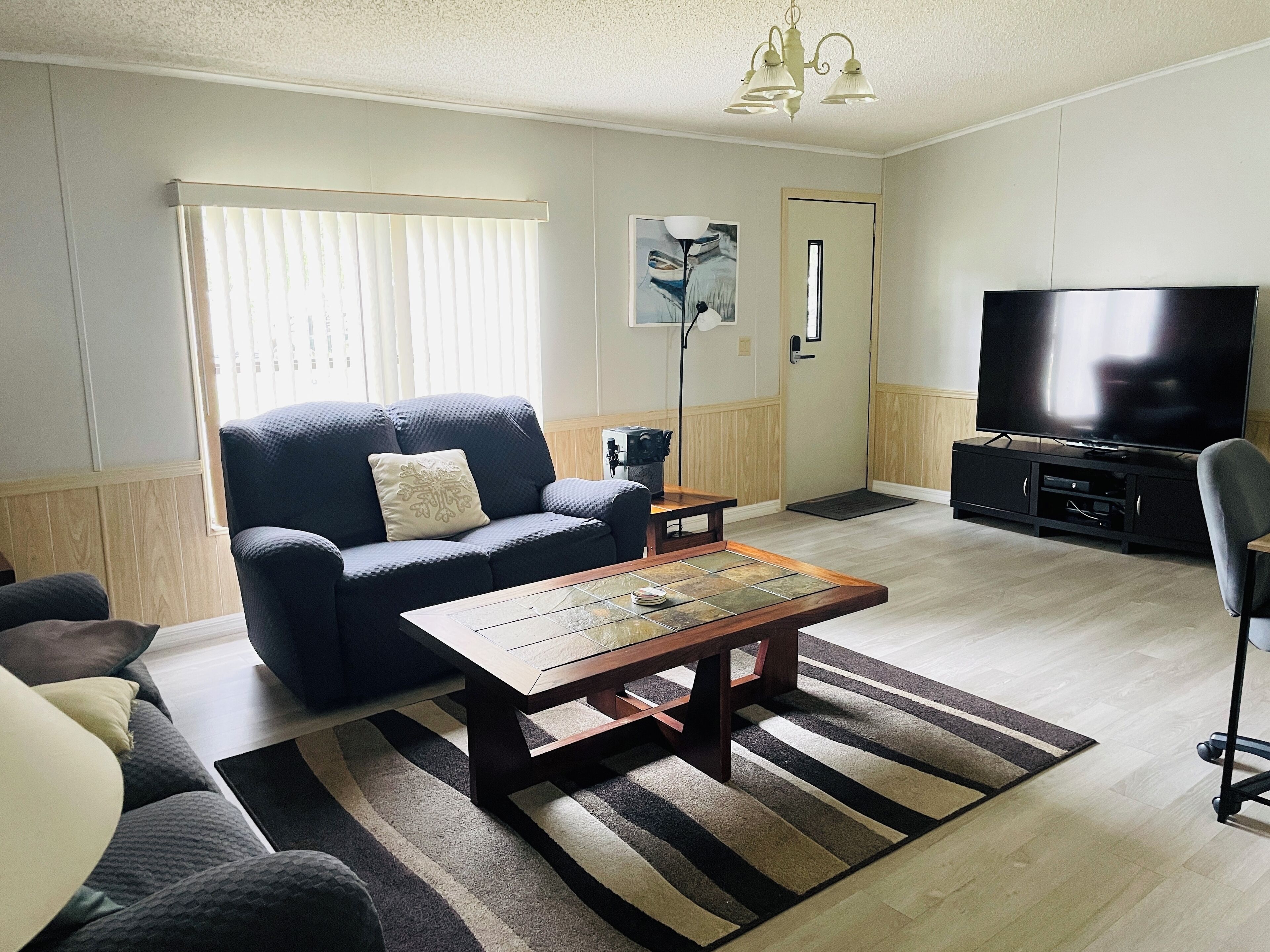 A living room with a sofa, coffee table, TV, and a painting on the wall.