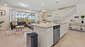 A spacious kitchen with a central island, white cabinetry, and pendant lighting.