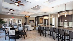A spacious hotel lobby with a bar area, multiple seating arrangements, and ceiling fans.