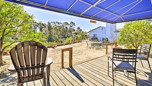 Eine überdachte Terrasse im Freien mit Holzboden, Metallstühlen und einem Tisch.