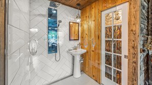 A bathroom with white tiles, a wooden door, and a sink. - Wilderness Country Inn: France (Mentone)