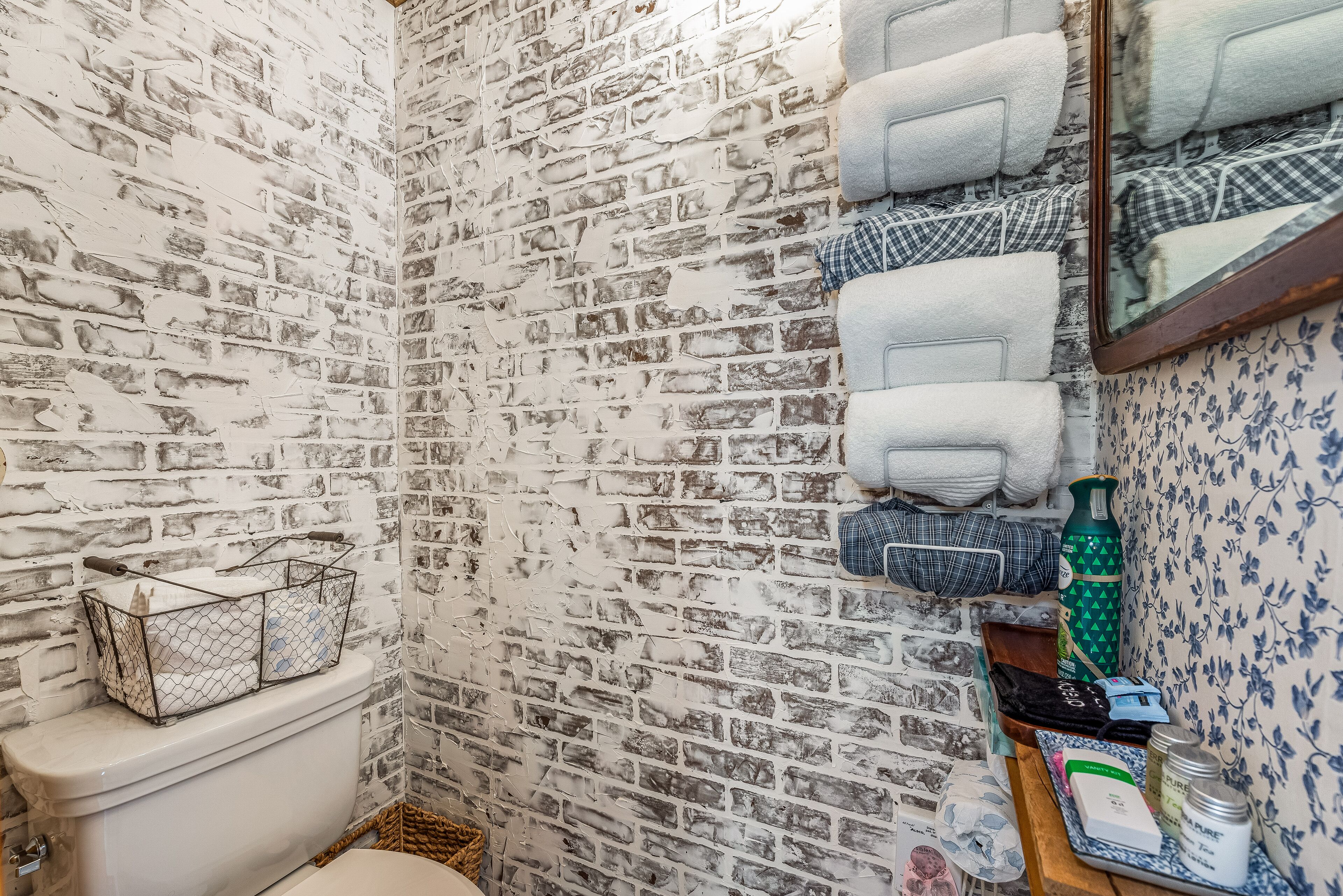 A bathroom with a brick-patterned wall, a toilet, a sink, and towels hanging on the wall.