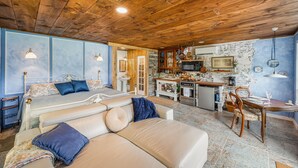 A cozy living area with a sofa, a dining table, and a kitchen in the background. - Wilderness Country Inn: France (Mentone)