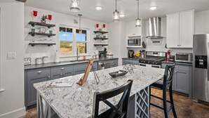 A modern kitchen with granite countertops, stainless steel appliances, and pendant lighting. - Texas Hill Country Escape in Hye, TX (Hye)