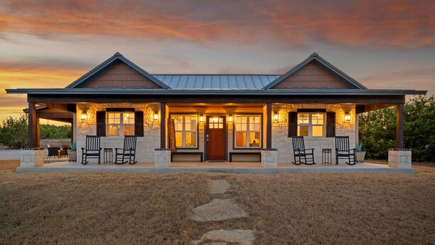 A two-story house with a covered porch, stone exterior, and a pathway leading to the entrance. - Texas Hill Country Escape in Hye, TX (Hye)