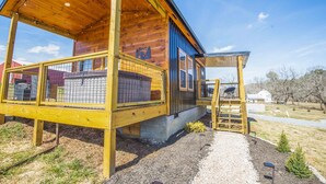 Une cabane en bois dotée d’un porche couvert, d’un espace clos et d’un chemin de gravier menant à l’entrée.