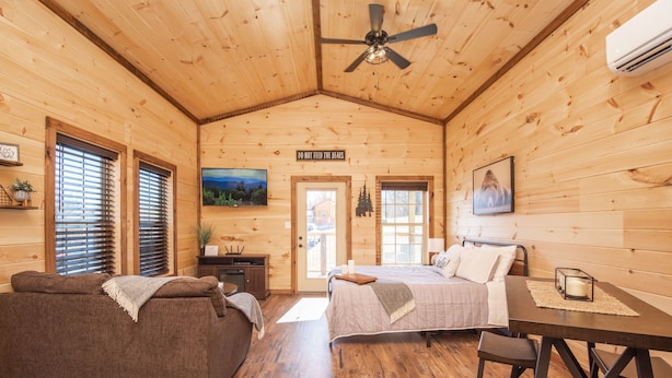 L'intérieur d'un chalet en bois, avec un lit, un canapé et une table à manger.