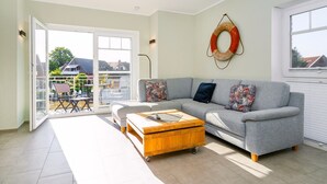 A living room with a grey sofa, wooden coffee table, and a large window.