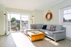 A living room with a grey sofa, wooden coffee table, and a large window.