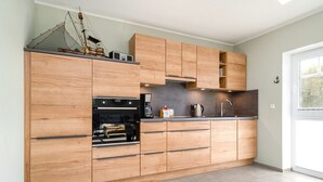 Eine moderne Küche mit Holzschränken, einem Einbauofen und einer Kaffeemaschine.