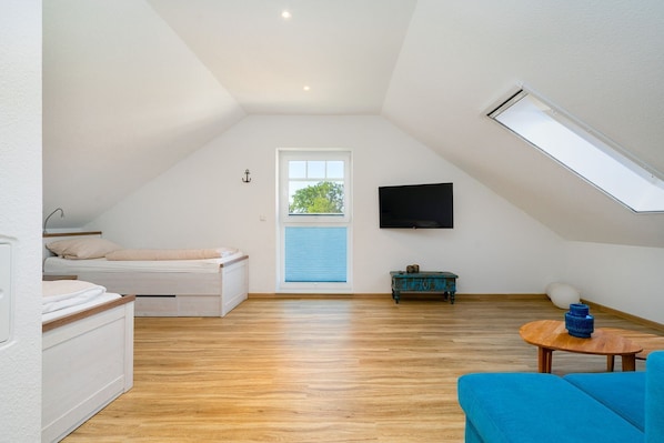 Une pièce avec un lit en mezzanine, une télévision, une petite table et un canapé bleu.