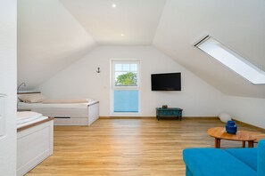Une pièce avec un lit en mezzanine, une télévision, une petite table et un canapé bleu.