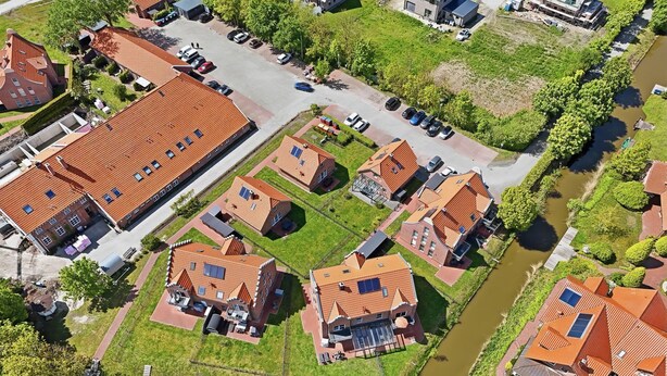 An aerial view of a residential area with houses, a river, and a parking lot.