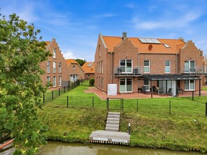 A residential building with a brick facade, a covered outdoor seating area, and a small water feature.