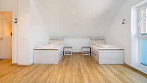 A small, single-room apartment with two beds, a window, and a door.