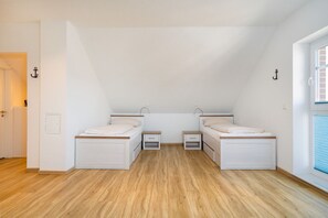 Eine kleine Einzimmerwohnung mit zwei Betten, einem Fenster und einer Tür.