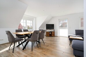 En moderne loftlejlighed med spiseplads, opholdsstue og fjernsyn på et træstel.