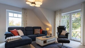 A modern living room with a sofa, armchair, coffee table, and a lamp.