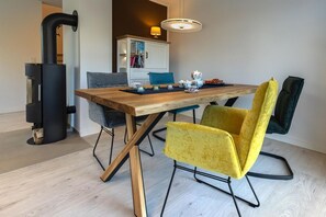 Un coin repas avec une table en bois, deux chaises, une cheminée noire et une bibliothèque.